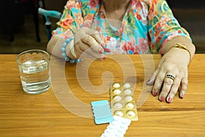 Health care concept fat senior woman hand holding pills and glass water