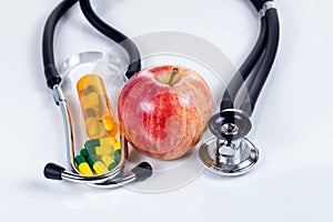 Health care concept with medicine plus red apple with stethoscope