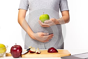 Health care concept. Pregnant mother hold green apple or fruit for eating. It is healthy food for fetus, pregnant woman. Mom care