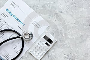 Health care costs with billing statement, stethoscope and calculator on stone table top view mockup