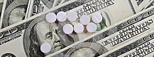 Health care costs US dollars with pills. White pills are a cure and the high cost of medicine
