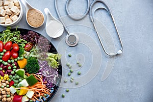 Health Care.  Fresh vegetable salad with medical stethoscope and equipment dumbbell for diet