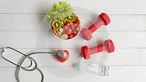 Health Care.  Fresh vegetable salad with medical stethoscope and equipment dumbbell for diet