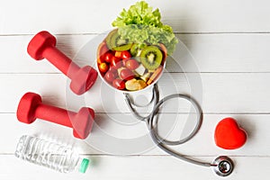 Health Care.  Fresh vegetable salad with medical stethoscope and equipment dumbbell for diet and weight loss