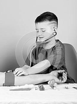 Health care. Kid little doctor sit table with stethoscope and medical tools. Medicine concept. Measuring blood pressure