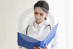 Health care and medical concept. Professional woman doctor wear coat uniform with stethoscope reading information or data disease