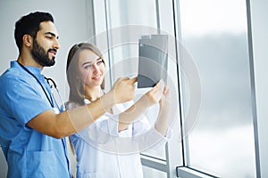 Health Care. Medical Team Examining X-ray Report in Corridor. Me