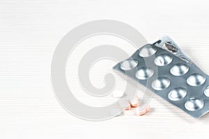 Health care and medicine.Close-up image of white and pink medicines for stomach pains and antibiotics on white wooden background