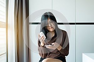 Health care and people concept,Asian woman using cell phone searching information and reading drug or pill label and prescription