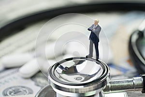 Health care, pharmaceutical and medical industry business concept, miniature businessman standing on stethoscope and white tablet