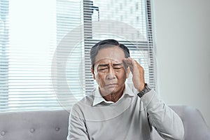 Health care, stress, old age and people concept - senior man suffering from headache at home