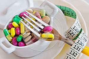 Health care and wellness - diet pills and loosing weight - various tablets in a pot with forks