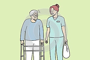 Health care worker helps elderly disabled person with walking frame.