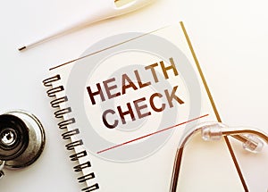 Health Check written on medical notebook with stethoscope and thermometre