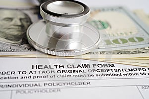 Health claim form with stethoscope and US dollar banknotes, insurance accident medical concept