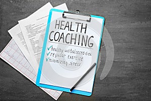 Health coaching written on sheet of paper with medical documents on grey background