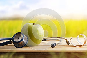 Health concept with apple stethoscope and tape measure in nature