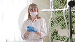 Health concept. Portrait of hospital nurse rubbing her hands in gloves with anti-bacterial liquid antiseptisizing them