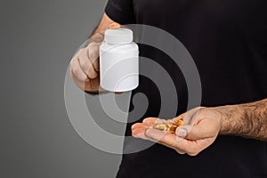 Man holding a bottle and supplements in hand photo