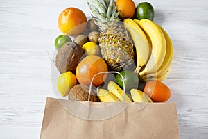 Health diet. Paper bag of different fruits on white wooden background.