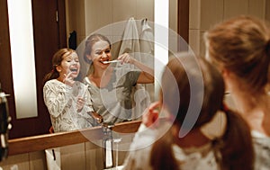 Health and hygiene of oral cavity. mother and child daughter brush their teeth in   bathroom in front of a mirror