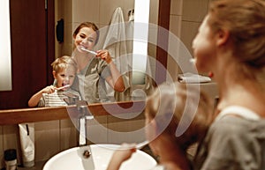Health and hygiene of   oral cavity. mother and child son brush their teeth in   bathroom in front of a mirror