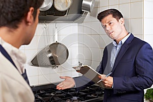 Health Inspector Meeting With Chef In Restaurant Kitchen photo