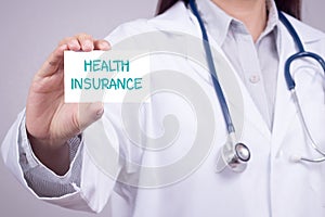 Health insurance concept. doctor in medical clothing with stethoscope showing card for health insurance in hand, anonymous face.