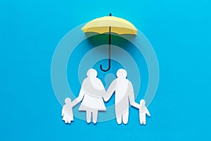 Health insurance concept. Family cutout under umbrella on blue background top-down copy space