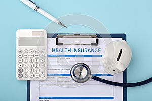 Health insurance document with stethoscope, calculator and piggy bank
