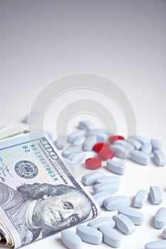 Health insurance, medical ethics concept. Red and blue pills on white background next to a wad of cash.