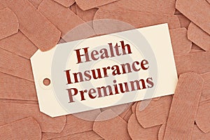 Health insurance premiums message on a gift tag with lots of fabric adhesive band aids
