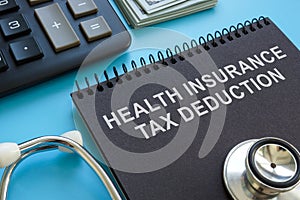 Health insurance tax deduction inscription, stethoscope and calculator.