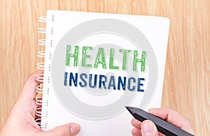 Health Insurance word on white ring binder notebook with hand ho
