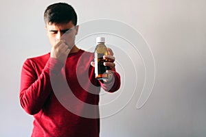 Health and Medicine Concept: Young boy cold dressed in red holding a cough syrup