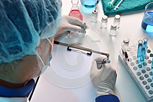 Health personnel with vials on the table writing in folder