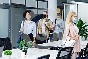 Health protection and return to work after quarantine covid-19. Multiracial young employees in protective masks go to photo