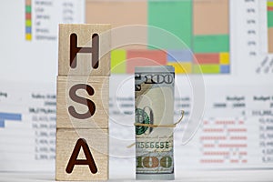 Health Savings Account HSA concept with white piggy bank, stethoscope wood block letters and green background