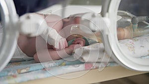 health, small defenseless newborn child after surgery in an oxygen mask lies in pressure chamber under supervision of