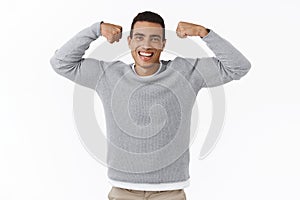 Health and sport. Happy cheerful smiling young athletic man, flex biceps and laughing, getting strong, workout to gain