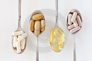 Health supplements on teaspoons against white background