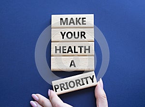Health symbol. Wooden blocks with words Make your health a Priority. Doctor hand. Beautiful deep blue background. Health concept.