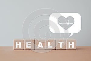 Health text on wooden cube block with heart and pulse sign inside white speech bubble including copy space, For wellness,