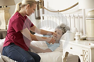 Health Visitor Giving Senior Woman Glass Of Water In Bed At Home photo