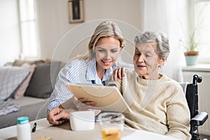 A health visitor measuring a blood pressure of a senior woman at home.