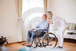 Nurse and senior man in wheelchair during home visit.