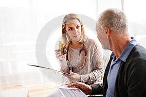 Health visitor and a senior man with tablet during home visit.