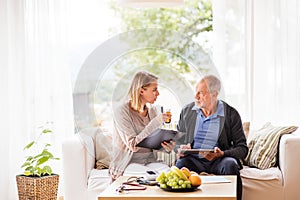 Health visitor and a senior man with tablet during home visit.