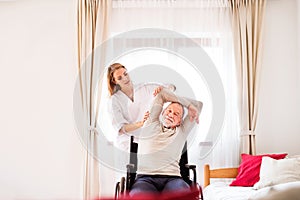 Nurse and senior man in wheelchair during home visit.