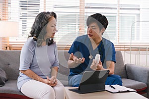 Health visitor and a senior woman with tablet during home visit. Elderly healthcare and Home health care service concept